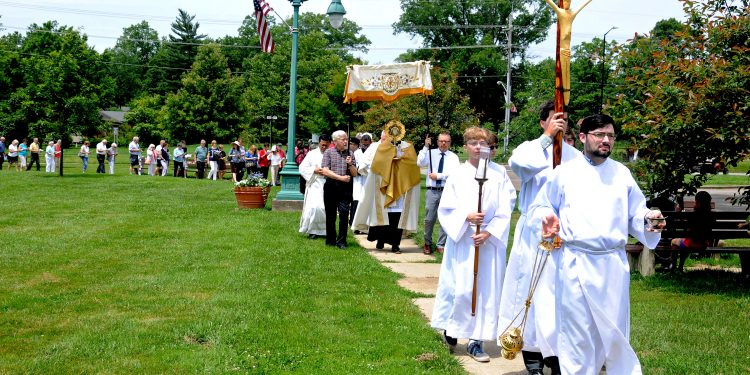 Our Lady of the Rosary parishioner Joshua Vietas leads the congregation around the Greenhills Commons during the parish's Fourth Annual Feast of Corpus Christi Procession on Sunday, June 23. Members of the church process to the Commons's gazebo where the Blessed Sacrament is displayed during a brief service. Following a homily by Our Lady of the Rosary pastor, Fr. Alex McCullough, the Blessed Sacrament is returned to the church for a final blessing and placed in the tabernacle. (CT Photo/ David A. Moodie,)