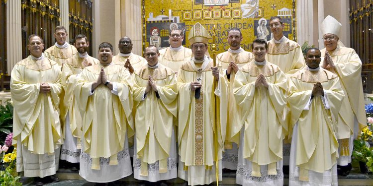 Front Row from L to R: Father Anthony Brausch, Father Mark Bredstege, Father Jeff Stegbauer, Archbishop Dennis M. Schnurr, Father Andrew Hess, Father Alex Biryomumeisho; Back Row L to R, Father Ambrose Dobrozsi, Father Elias Mwesigye, Father Zach Cecil, Father Jedidiah Tritle, Father Christian Cone-Lombarte, and Bishop Joseph Binzer (CT Photo/Greg Hartman)